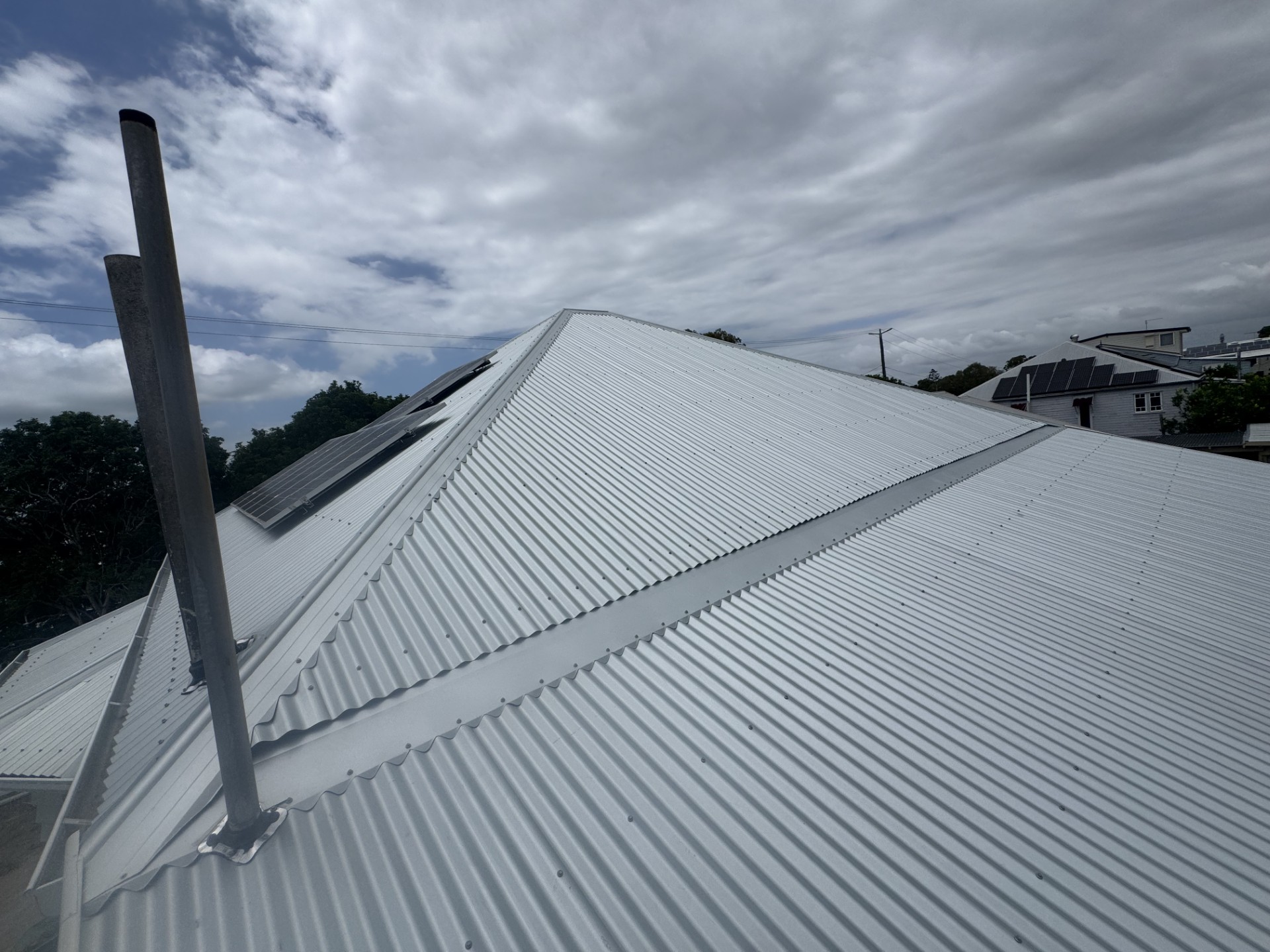 Crisp metal roof installation in Logan under cloudy skies